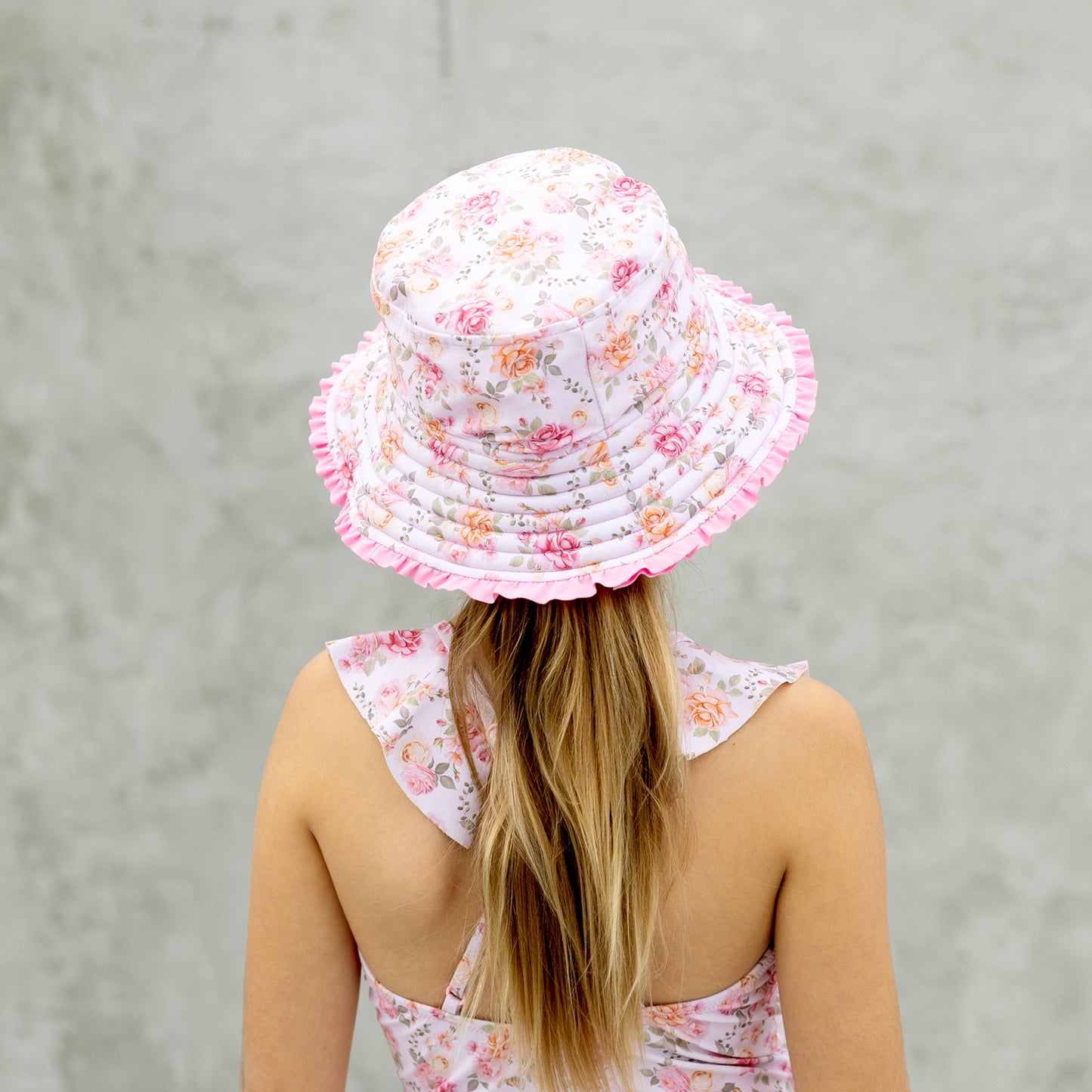 Person wearing a floral bucket hat and dress against a plain background