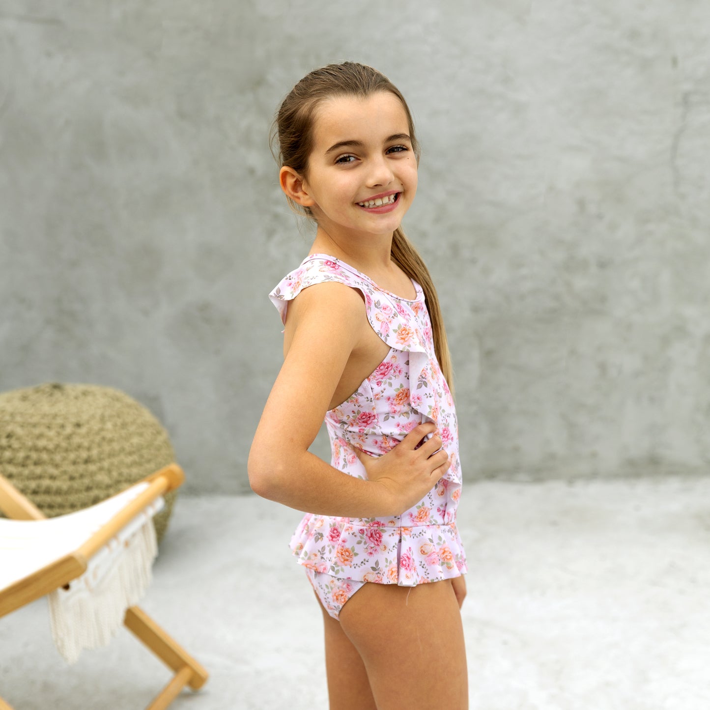 Young girl wearing a floral outfit standing against a neutral background