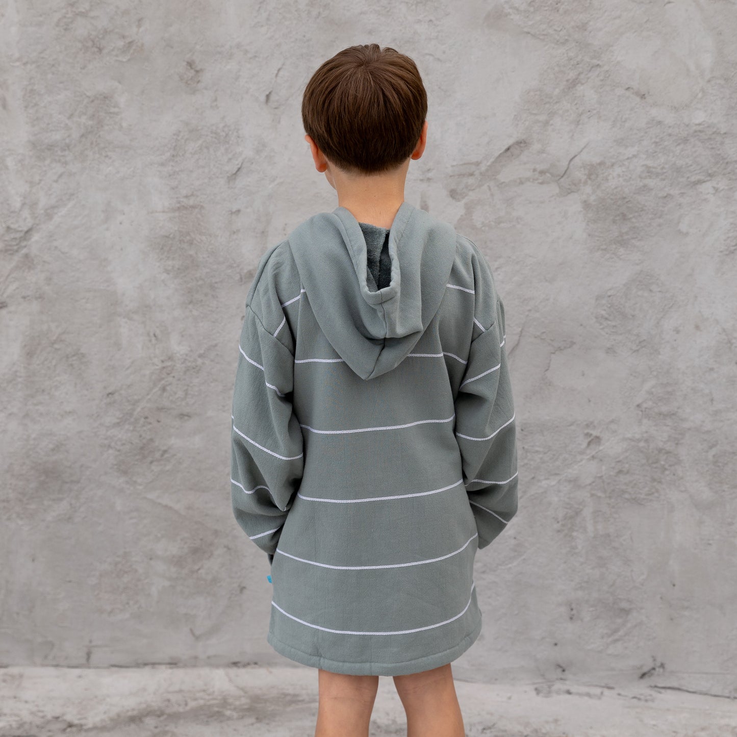 Person wearing a gray striped robe against a concrete wall