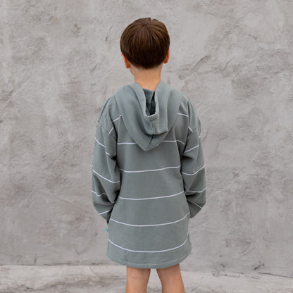 Person wearing a gray striped robe against a concrete wall