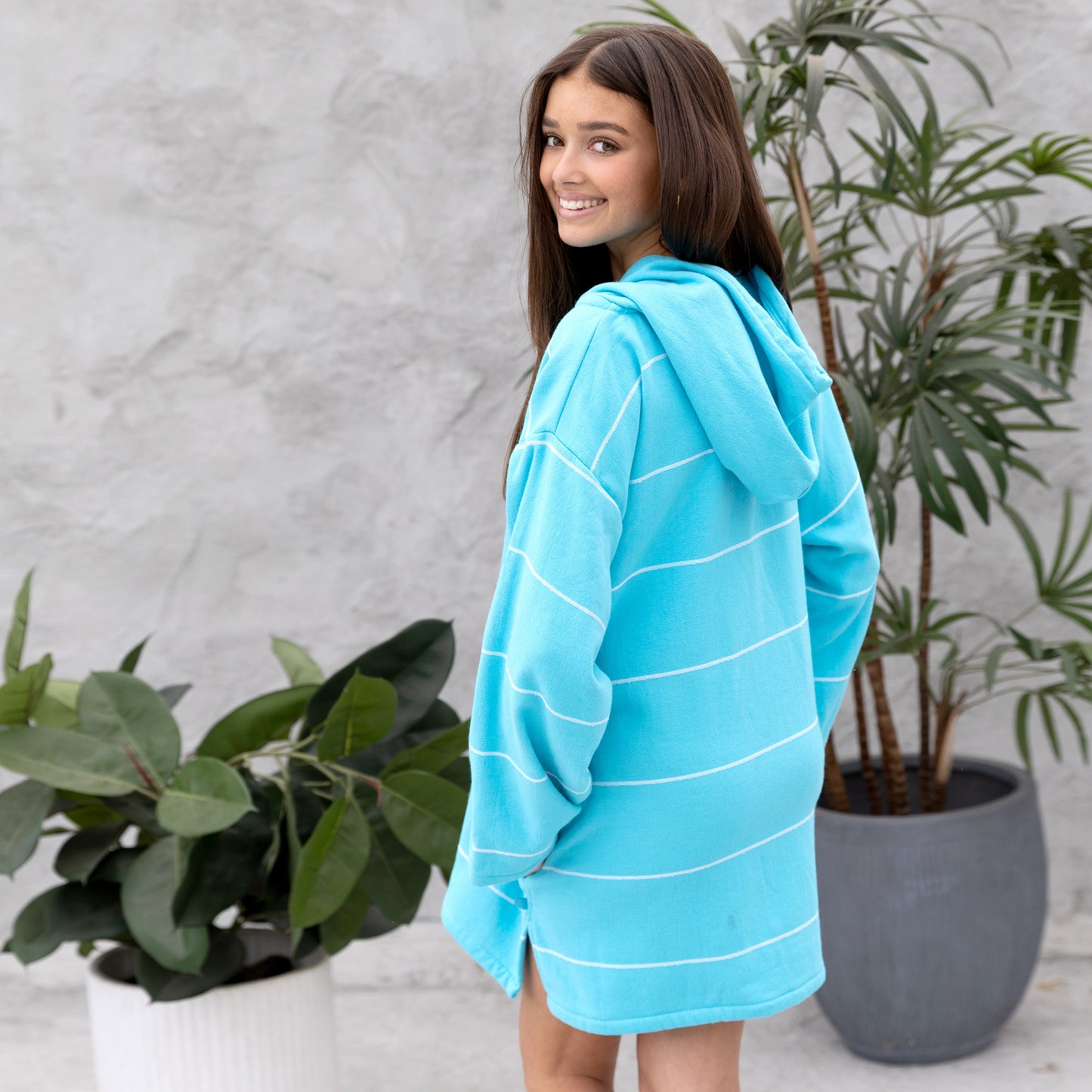 Person wearing a blue striped towel with plants in the background