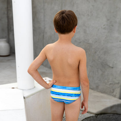 Young boy wearing a colorful striped boys swim racer against a neutral background