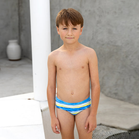 Young boy wearing a colorful striped boys swim racer against a neutral background
